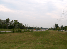 A rural highway with a wide right-of-way vanishes into the distance.