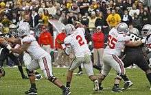 A quarterback throws while an offensive lineman blocks for him.