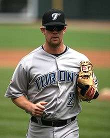 A man in a grey baseball jersey and black hat with a script "J".