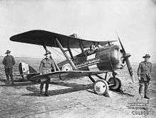 Biplane with soldiers wearing slouch hats standing around it.