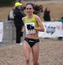 A pale woman runs through a muddy path.