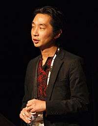 Photo of a Japanese man in a black jacket in front of a black background.