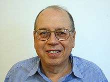 Shoulder high portrait of man in his sixties in a checked shirt with a blank white background