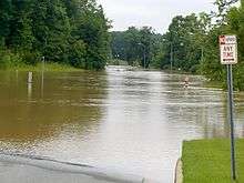 A road entirely submerged with murky flood waters.