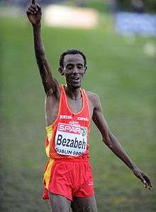 A slender man raises his arm in victory on a grassy course.