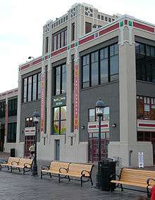 Tall modern building with big windows. Benches are in front.