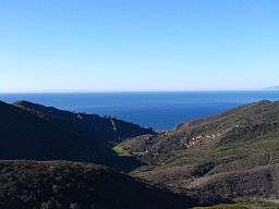 A large valley between arid chaparral-covered hills, opening towards the ocean.