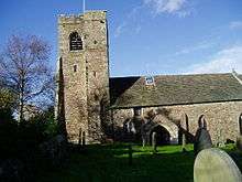 A simple stone church seen from the south, with a west tower.