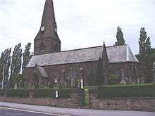 A stone church with an apsidal chancel and a broach spire