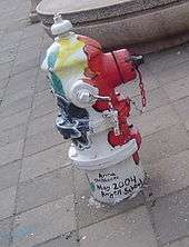 A painted hydrant with vertical stripes of multiple colors