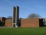 A low red-brick building whose off-centred entrance is dominated by two tall vertical concrete fins