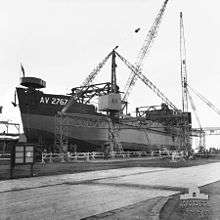 Black and white photo of a ship out of the water surrounded by five cranes