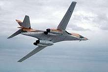  A B-1A flying with its wings swept back, showing its underside