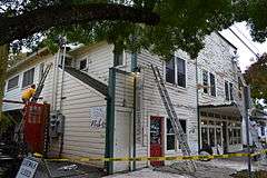 Photograph of a two-story, wooden building being painted