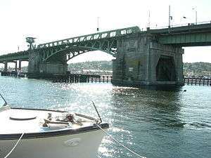 An aging concrete and steel bridge crossing calm waters on a sunny day