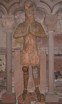 A grave effigy, standing, in armour, with hands together in prayer