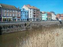 Three and four storey buildings on the far side of a river.