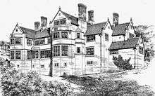 A large house on sloping ground with two storeys, a basement and attics. There are prominent gables, bay windows and tall chimneys.