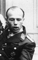 The head and shoulders of a young man. He wears a military uniform, an Iron Cross displayed at the front of his shirt collar and breast pocket.