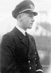 A black-and-white photograph of a man in semi profile wearing a dark military uniform and peaked cap.