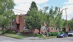 Photograph of a two-story, brick apartment building on a street corner