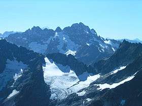 A large, rugged mountain rises above a snowy ridge