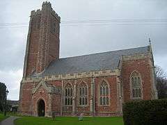 Red stone church with square tower.