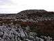 A mound of  rough gritstone on a summit of stone and heather