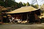 Wooden building with a hipped roof, slightly raised floor, an enclosing veranda and a wide central staircase on the front.