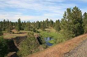 A rail trail overlooking a stream in a shallow valley