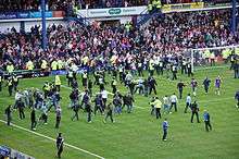 A large number of spectators running onto the field