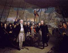 On the deck of a sailing warship, with men in blue and red military uniforms standing in a line, a man in a long blue coat passes a sword to a large man in a short, open blue coat, who holds his hands wide with their palms flat. In the background several ships in various states of disrepair drift between columns of smoke with the sun low on the horizon.