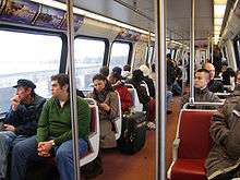 Passengers sit in fixed two-seat units. There are metal poles and bars for standees to hold.