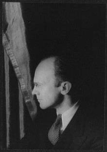 A black-and-white photograph of the upper portion of a man in glasses, looking leftward.