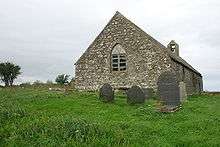 A simple stone church seen almost from the east end. The east window has two lights and a slightly pointed arch, and at the far end the bellcote can be seen