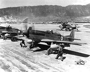 Two piston engined fighter aircraft lined up ready for take-off on a runway.