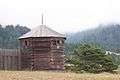 Photograph of a reconstructed blockhouse and palisade wall at Fort Ross, a Northern California forestscape in the background.