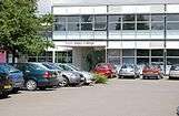 A busy car park in front of the entrance to a building