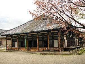 Wooden building with pyramid shaped roof and white walls.