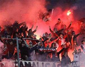 Cheering fans in a cloud of pink smoke