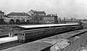 A black-and-white photograph showing a 6-car train at a station. There are detail differences in the carriages, the leading car, unlike the others, has its clerestory extended to the car end and the 3rd and 5th carriage sides are flared at the bottom.