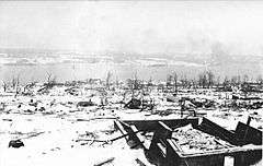 Destroyed buildings, with harbour in background