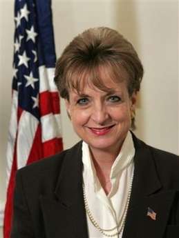 Woman smiling with American flag behind her.