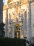 The grand entry door at the Hearst San Simeon Estate, with a great quantity of carved stonework, illuminated in the golden evening sun.