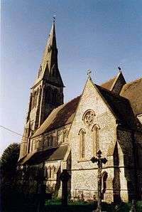 The tower, nave and south chapel of a flint church is seen from the south.