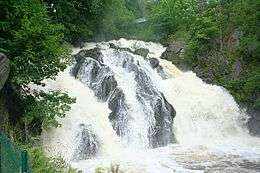 Steep cascading waterfall in a lush green canyon