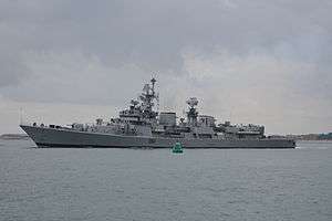 Long, grey ship passing a buoy