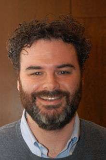 Head and shoulders photo of Greenberg smiling, with a beard and curly dark hair