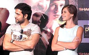 Koechlin sitting beside Emran Hashmi looking away from the camera