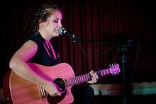 Loder singing and playing acoustic guitar onstage